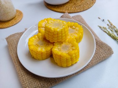 Tatlı mısır koçanları beyaz tabakta yarıya iniyor. 