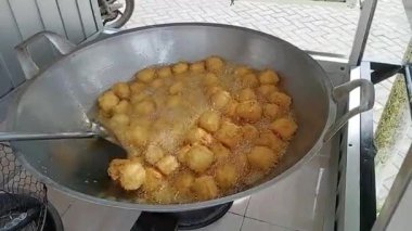 Tangerang, Endonezya, 19 Ağustos 2025. Bir ilkokulun önünde küçük kızarmış hamur aperatifleri hazırlayan ve kızartan bir sokak yemeği satıcısına yakın plan..