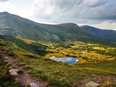 Parlak bir yaz gününde dağ gölü ve sıradağların manzarası. Ukrayna Karpatlarının çeşitliliği