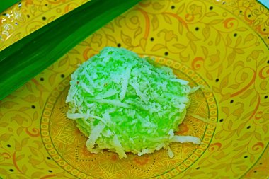 Discover the essence of Malaysian cuisine with our legendary dessert: a homemade delight of glutinous rice dough, coconut, and red palm sugar, cooked to perfection and served with coconut shreds. clipart