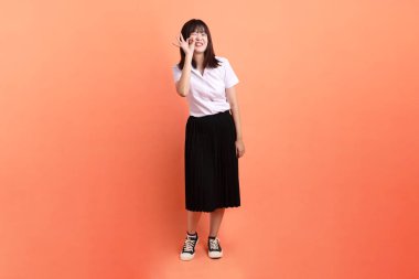 Tayland üniversitesi üniformalı neşeli bir bayan öğrenci. Ya iyi bir jestle ya da turuncu arka planda izole edilmiş olduğunu onaylıyor. Uluslararası Öğrenciler Günü, Dünya Öğrenciler Günü. Gen Z