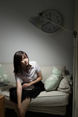 Tayland üniversitesi üniformalı genç bir kız öğrenci oturma odasında bir kanepede oturup ailesini bekliyor. Uluslararası Öğrenciler Günü, Dünya Öğrenciler Günü. Gen Z