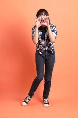 Mutlu SONGKRAN GÜNÜ. Turuncu arka planda izole edilmiş bağırma hareketleriyle yaz kıyafetleri içinde neşeli, sevimli, genç Asyalı kadın. Tayland Yeni Yıl Günü.