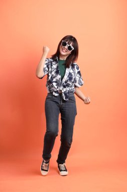 Mutlu SONGKRAN GÜNÜ. Yaz kıyafetleri içinde neşeli, genç Asyalı bir kadın. Heyecanlı, turuncu arka planda izole edilmiş bir şekilde kutluyor. Tayland Yeni Yıl Günü.