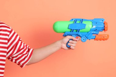 Turuncu arka planda plastik su tabancası var. Songkran festivali. Tayland Yeni Yıl Günü.