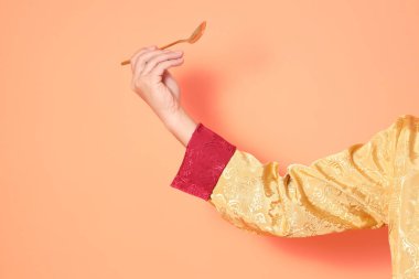 Yeni Çin yılın kutlu olsun. Asya 'lı son sınıf öğrencileri, geleneksel altın kıyafetler giyip turuncu arka planda altın kaşıkla el ele tutuşuyorlar..