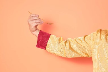 Yeni Çin yılın kutlu olsun. Asya 'lı son sınıf öğrencileri, geleneksel altın kıyafetler giyip turuncu arka planda altın kaşıkla el ele tutuşuyorlar..