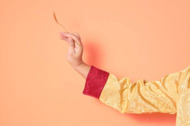 Yeni Çin yılın kutlu olsun. Asya 'lı son sınıf öğrencileri, geleneksel altın kıyafetler giyip turuncu arka planda altın kaşıkla el ele tutuşuyorlar..