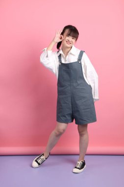 Tulum giymiş, pembe arka planda izole edilmiş bir poz veren neşeli, sevimli, genç Asyalı kadın. Sevgililer Günü, Kadınlar Günü, Doğum Günü