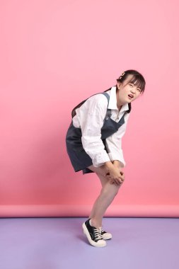 Pembe arka planda izole edilmiş hastalıklı hareketleriyle günlük kıyafetler giyen neşeli, sevimli, genç Asyalı kadın. Sevgililer Günü, Kadınlar Günü, Doğum Günü