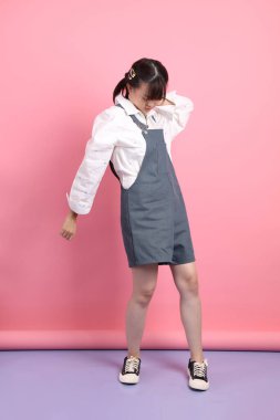 Pembe arka planda izole edilmiş hastalıklı hareketleriyle günlük kıyafetler giyen neşeli, sevimli, genç Asyalı kadın. Sevgililer Günü, Kadınlar Günü, Doğum Günü