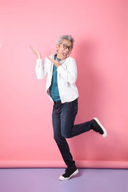 Gözlüklü, Asyalı, enerjik, üst düzey bir adam kahverengi arka planda izole edilmiş ve günlük kıyafetlerle poz veriyor. Olgun adam, Asyalı adam. Yaşlı, stüdyo fotoğrafı. Çoklu duygular.