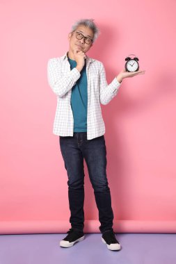 Asyalı enerjik kıdemli adam günlük kıyafetler giyiyor. Pembe arka plan, zaman yönetimi, denge...