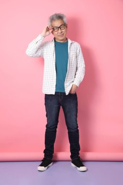 Pembe arka planda izole edilmiş ciddi bir jestle sıradan giyinmiş Asyalı kıdemli bir adam. Sevgililer Günü