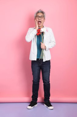 Pembe arka planda izole edilmiş bir çiçek buketi tutan sıradan giyinmiş Asyalı son sınıf öğrencisi. Sevgililer Günü, Kadınlar Günü, Doğum Günü