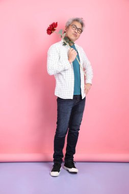 Pembe arka planda izole edilmiş bir çiçek buketi tutan sıradan giyinmiş Asyalı son sınıf öğrencisi. Sevgililer Günü, Kadınlar Günü, Doğum Günü
