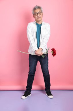 Pembe arka planda izole edilmiş bir çiçek buketi tutan sıradan giyinmiş Asyalı son sınıf öğrencisi. Sevgililer Günü, Kadınlar Günü, Doğum Günü