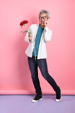 Pembe arka planda izole edilmiş bir çiçek buketi tutan sıradan giyinmiş Asyalı son sınıf öğrencisi. Sevgililer Günü, Kadınlar Günü, Doğum Günü