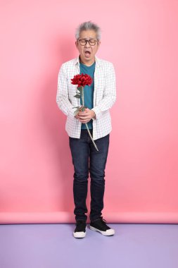 Pembe arka planda izole edilmiş bir çiçek buketi tutan sıradan giyinmiş Asyalı son sınıf öğrencisi. Sevgililer Günü, Kadınlar Günü, Doğum Günü
