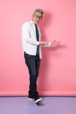 Pembe arka planda izole edilmiş baş parmak hareketleriyle sıradan giyinmiş Asyalı son sınıf öğrencisi. Sevgililer Günü