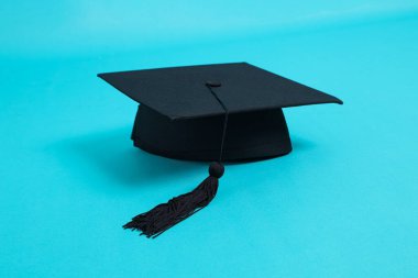Siyah Mezuniyet Başlığı veya Mortarboard mavi arkaplanda izole edilmiş siyah püsküllü.