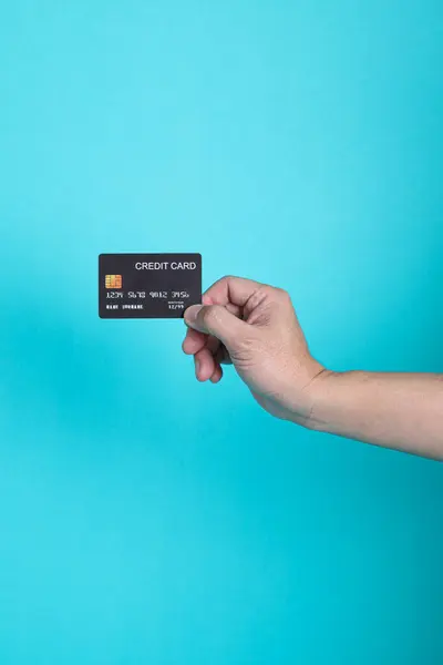 Mavi arka planda bankanın kredi kartı erkek elinde.