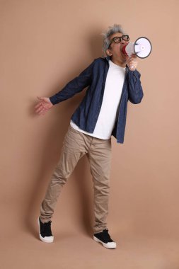 Asyalı bir adam izole edilmiş kahverengi arka planda bir megafon tutuyor.