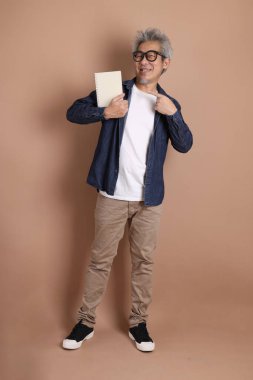 Asyalı adamlar ellerinde kahverengi arka planda bira bardağı tutuyorlar. Stüdyo fotoğrafı.