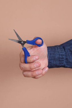 Kahverengi arka planda izole edilmiş Asyalı erkek eli makasına yakın çekim