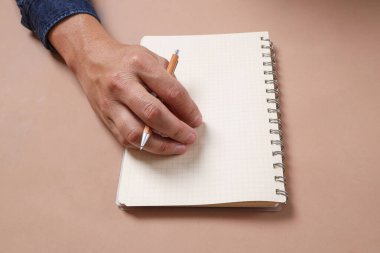 Asyalı erkekler el ele kitap ya da spiral defter tutarlar. Kahverengi arka planda, stüdyo çekimlerinde, kitap okurken, kitap kurdu.