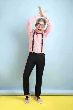 Kırmızı fiyonklu Asyalı kıdemli adam dur işareti, çapraz yasak işareti, mavi arka planda izole edilmiş. Sevgililer Günü