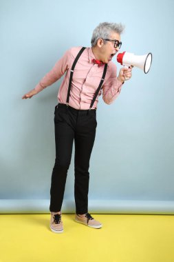 Asyalı, siyah askılı, kırmızı pruvalı, megafonu mavi arka planda tutan son sınıf öğrencisi. Sevgililer Günü