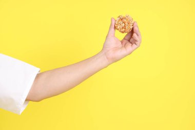 Pirinç krakeri tutan eller sarı arka planda izole edilir. Çin vejetaryen festivali 9 imparator tanrı, J festivali.