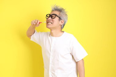 Çin Vejetaryen Festivali. Sarı arka planda izole edilmiş diş fırçası jesti olan beyaz giysili yaşlı bir adam. Dokuz imparator Tanrı, J festivali.