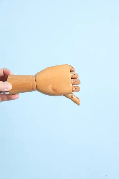 Hand of mannequin shake hands with gusture of thumb up on isolated blue background. Symbol, teamwork.