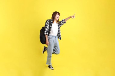 Okul çantasında yürürken ekose gömlek giyen bir üniversite öğrencisi. Eğitim, yurtdışında eğitim, Z jenerasyonu, E-öğrenim. Ergen.