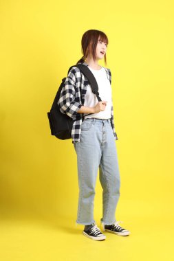 Ekose gömlek giyen Asyalı kız öğrenci okul çantası ve ders çalışma jesti ile kitap taşıyor. Eğitim, yurtdışında öğrenim, Z Geni, E-öğrenim.