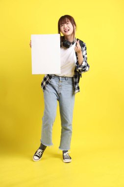 Ekose gömlek giyen Asyalı kız öğrenci okul çantası ve kulaklık taşıyor. Üzerinde boş tuval var. Eğitim, yurtdışında öğrenim, Z Geni, E-öğrenim.