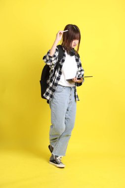 Ekose gömlek giyen Asyalı kız öğrenci okul çantası, ayakta durma ve tablet tutma hareketi taşıyor. Yurtdışında okumak, Z Geni, E-öğrenimi.