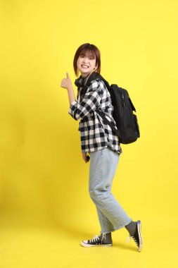 Ekose gömlek giyen Asyalı kız öğrenci okul çantası, ayakta durma ve tablet tutma hareketi taşıyor. Yurtdışında okumak, Z Geni, E-öğrenimi.