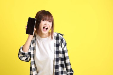 Asyalı üniversiteli kız öğrenci ekose gömlek giyiyor ve cep telefonu taşıyor. Eğitim, yurtdışında öğrenim, Z Geni, E-öğrenim.