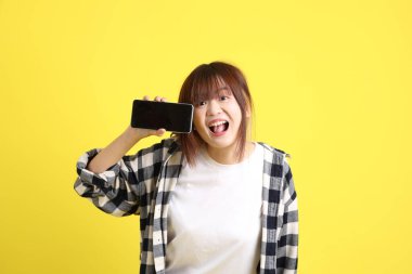 Asyalı üniversiteli kız öğrenci ekose gömlek giyiyor ve cep telefonu taşıyor. Eğitim, yurtdışında öğrenim, Z Geni, E-öğrenim.