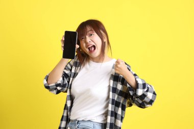 Asyalı üniversiteli kız öğrenci ekose gömlek giyiyor ve cep telefonu taşıyor. Eğitim, yurtdışında öğrenim, Z Geni, E-öğrenim.