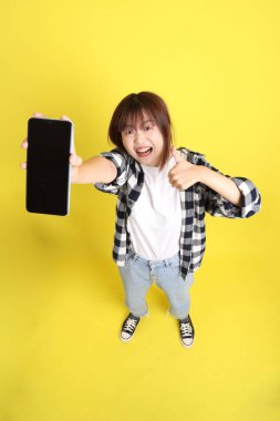 Asyalı üniversiteli kız öğrenci ekose gömlek giyiyor ve cep telefonu taşıyor. Eğitim, yurtdışında öğrenim, Z Geni, E-öğrenim.