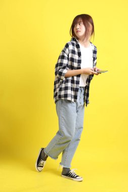 Asyalı üniversiteli kız öğrenci ekose gömlek giyiyor ve cep telefonu taşıyor. Eğitim, yurtdışında öğrenim, Z Geni, E-öğrenim.