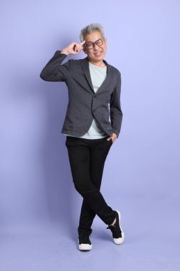 50 'li yılların Asyalı kıdemli işadamı, gözlüklü, resmi giyinmiş, mor arka planda soyutlanmış bir düşünce jesti.. 