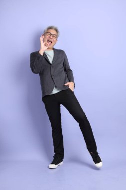 50 'lerin Asyalı kıdemli iş adamı, gözlüklü, resmi giyinmiş, iyi niyetli ya da mor arka planda izole edilmiş.. 