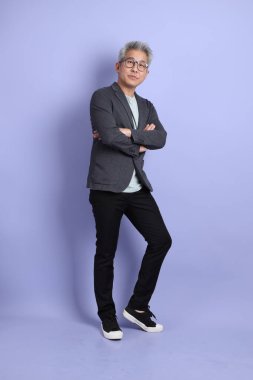 50 'li yılların Asyalı kıdemli iş adamı, gözlüklü, resmi kıyafetli, mor arka planda izole edilmiş bir jestle.. 