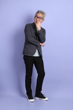 50 'li yılların Asyalı kıdemli iş adamı, gözlüklü, resmi kıyafetli, mor arka planda izole edilmiş bir jestle.. 