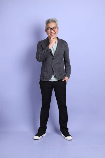50s asian senior businessman with glasses dressed in formal outfit with gesture of thinking isolated on purple background. 